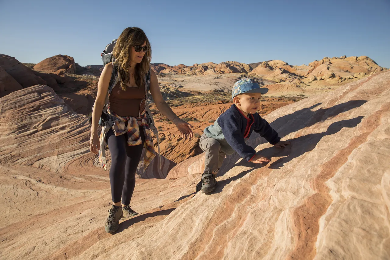 Mother supports her baby boy to climb a small hill, Yosemite National Park, U.S.A