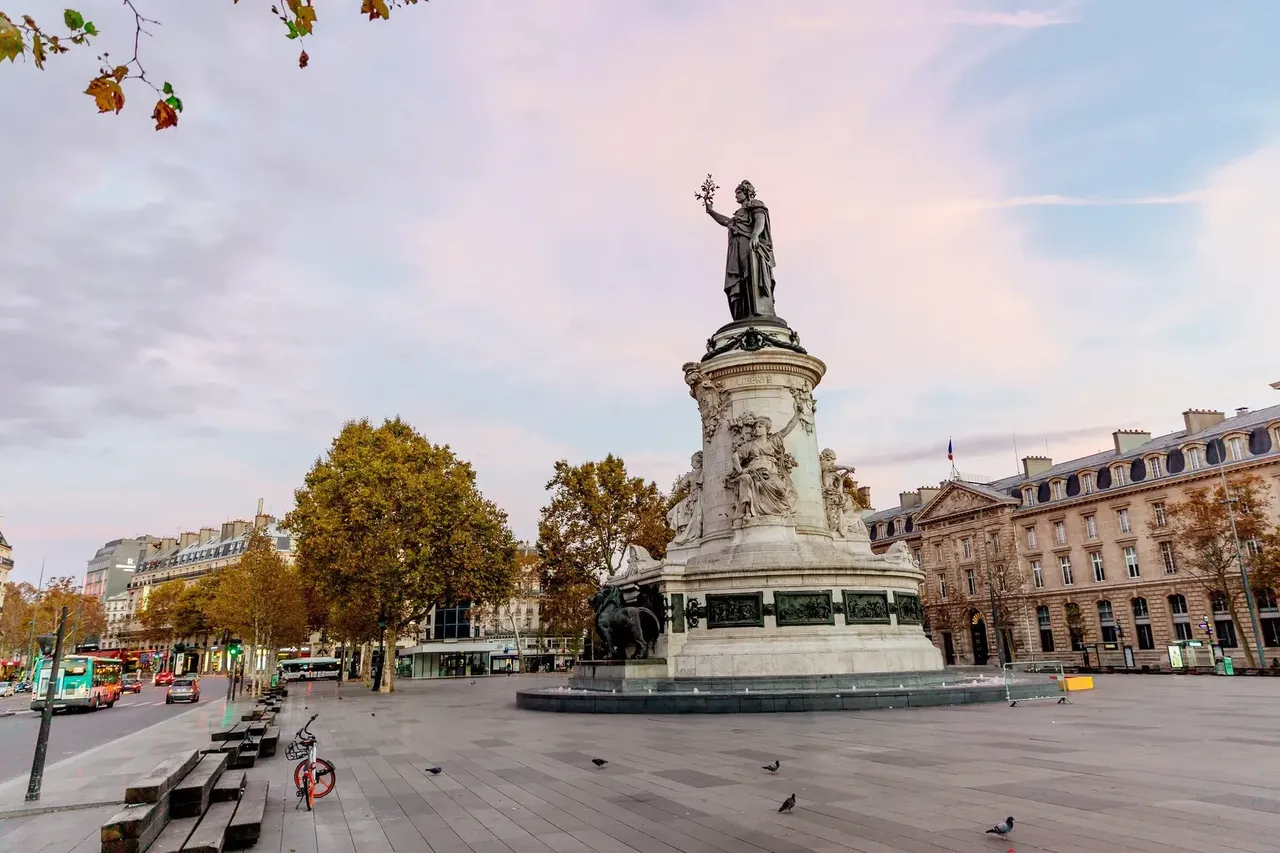 A stunning view of Place de la République bathed in the warm light of sunset, with the statue at the center prominently silhouetted.