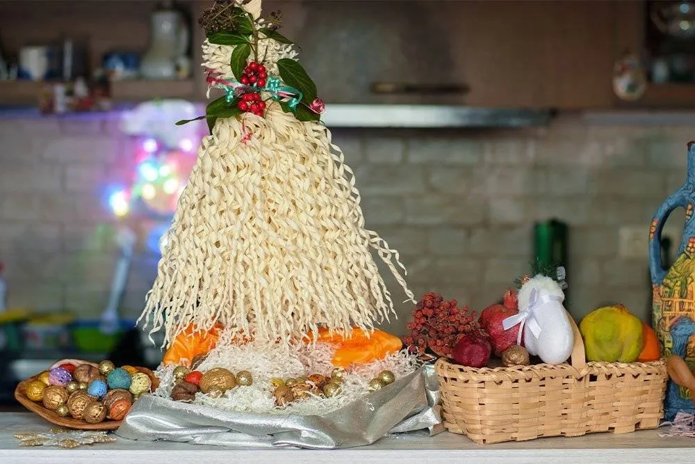Chichilaki in a Georgian kitchen with painted nuts underneath it — Shutterstock