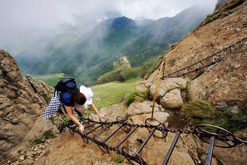 Hiker climbing up metal ladder along steep mountain trail in Drakensberg — Getty Images
