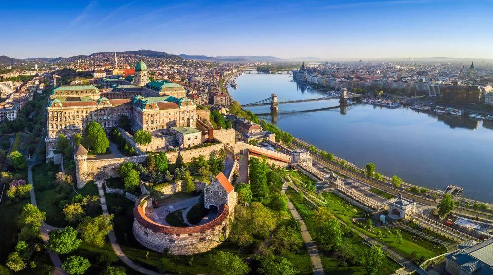 Budapest, Magyarország - A Budavári Palota, a Széchenyi Lánchíd, a Szent István Bazilika, a Parlament és a Mátyás-templom panorámaképe napfelkeltekor, kék égbolt.
