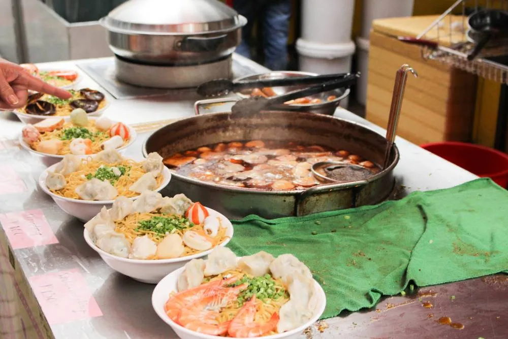Bowls of Chinese food on table surrounding large pot — Getty Images