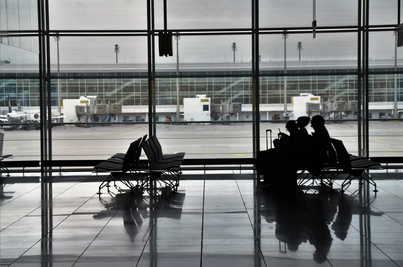Airport terminal with seated travelers waiting near the windows