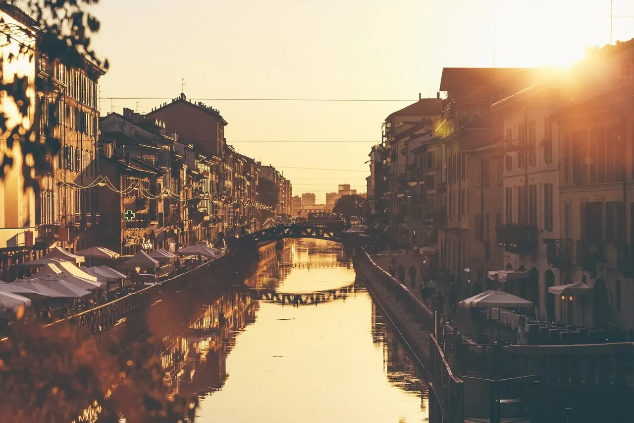 Naviglio Grande z barami przy brzegach o zachodzie słońce.