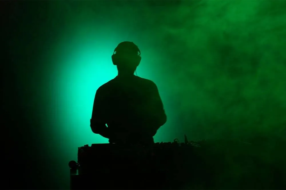 Silhouette of a DJ against green light — iStock