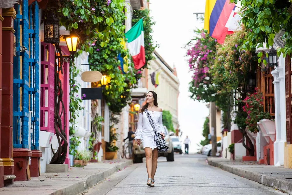 Woman walking down a flower-adored side streed in Cartagena