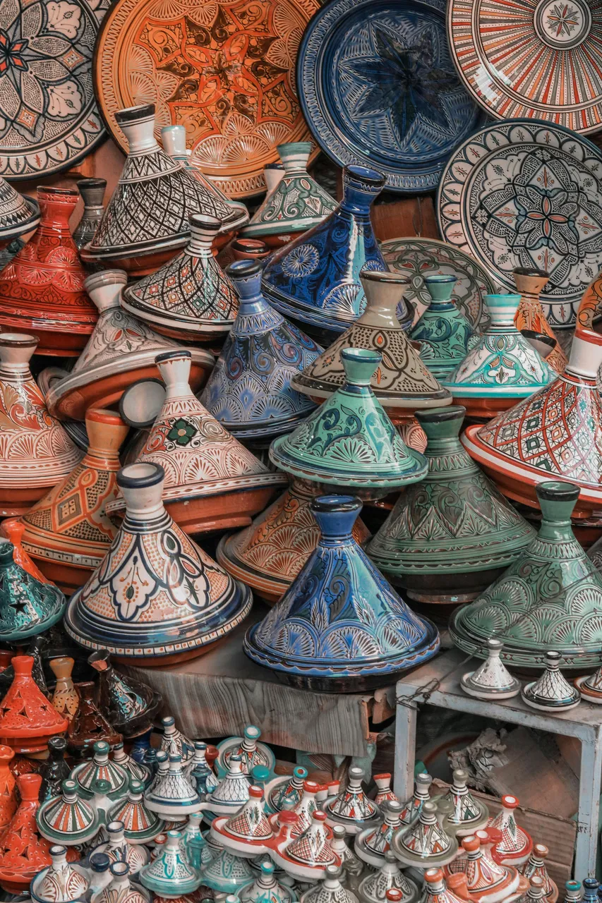 A close-up of colorful Moroccan tagine plates stacked neatly, showcasing intricate hand-painted patterns and earthy tones of clay and glaze.