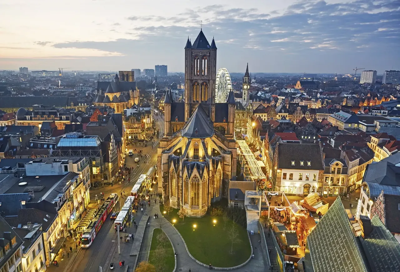 Enchanting aerial view of Ghent, Belgium, illuminated by golden lights reflecting on the canals at night