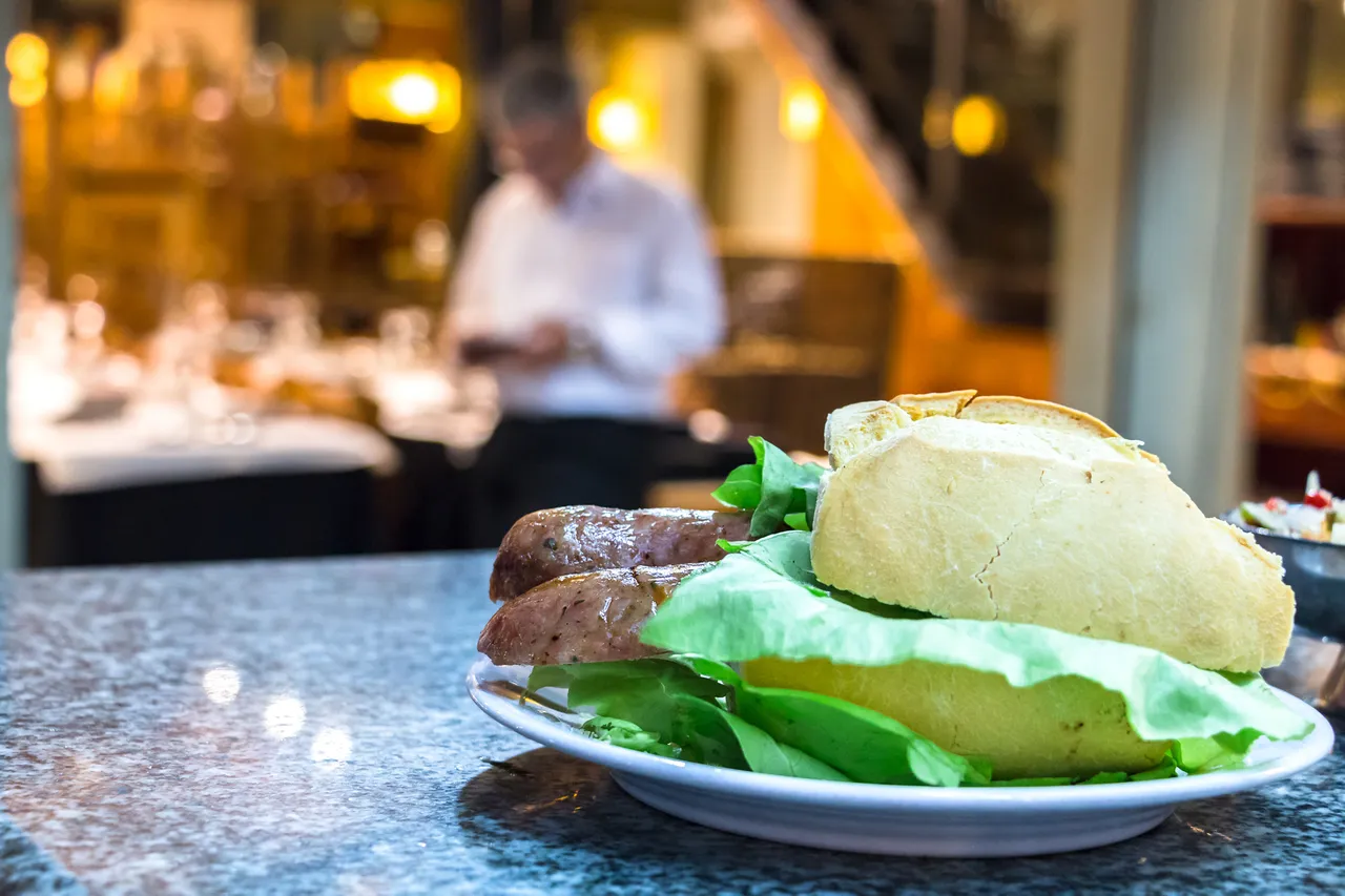 Kanapka choripan z sałatą i bułką na ladzie w Mercado Del Puerto, Montevideo, Urugwaj.
