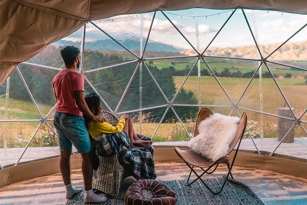 Couple looking at the scenic view from their glamping pod — Shutterstock