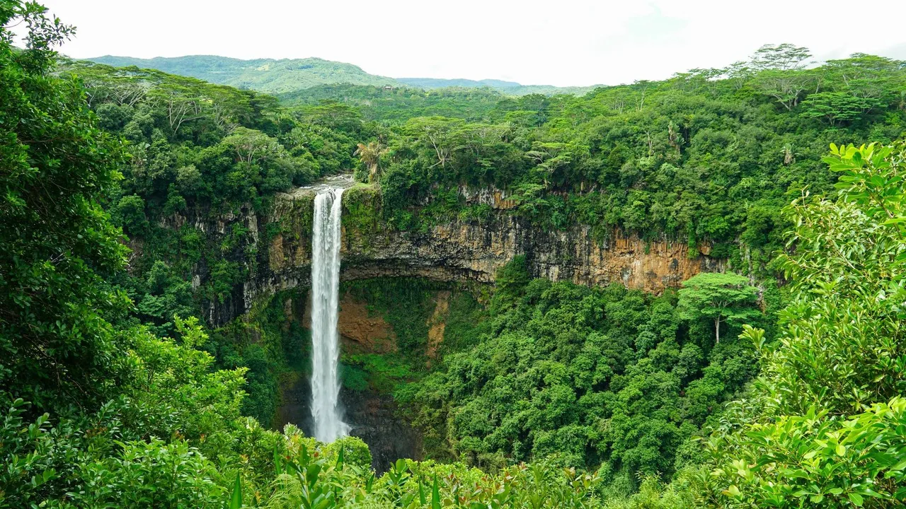 La impresionante cascada de Chamarel en Mauricio cae por un acantilado rocoso en un exuberante valle verde rodeado de vegetación tropical.
