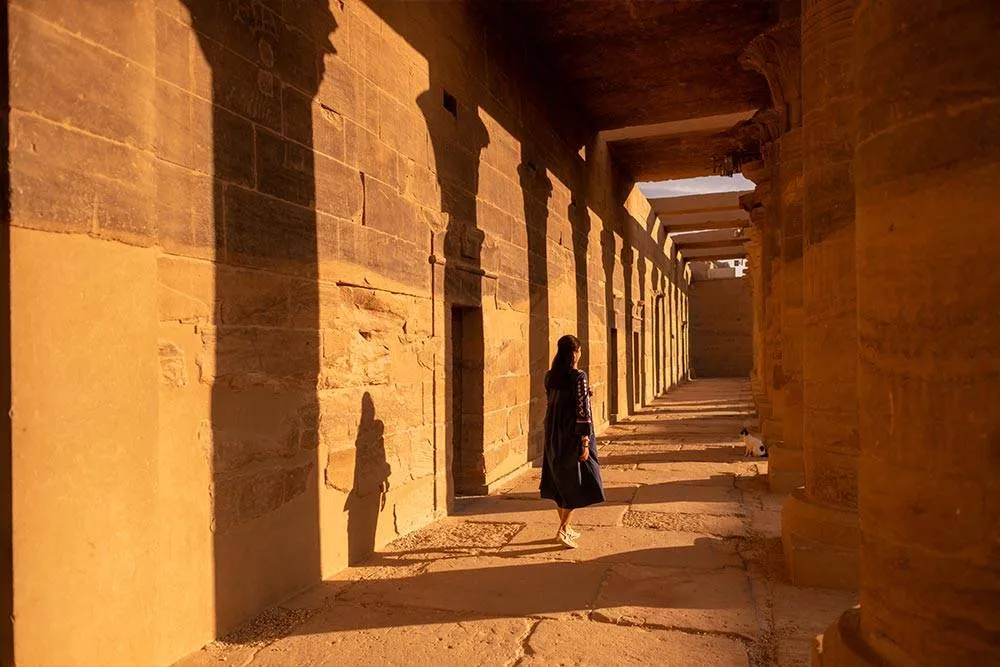 Woman walking between large ancient pillars of Egypt