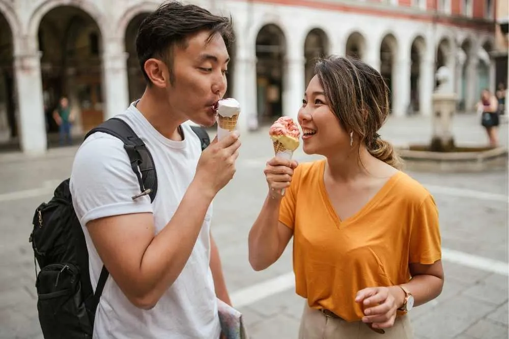 Azjatycka para w Wenecji jedząca lody na placu