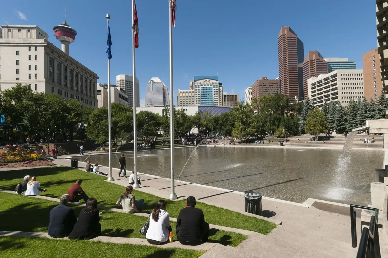 Daytime view of Olympic Plaza in Calgary, with its open plaza area, surrounding greenery, and the downtown skyline in the background.