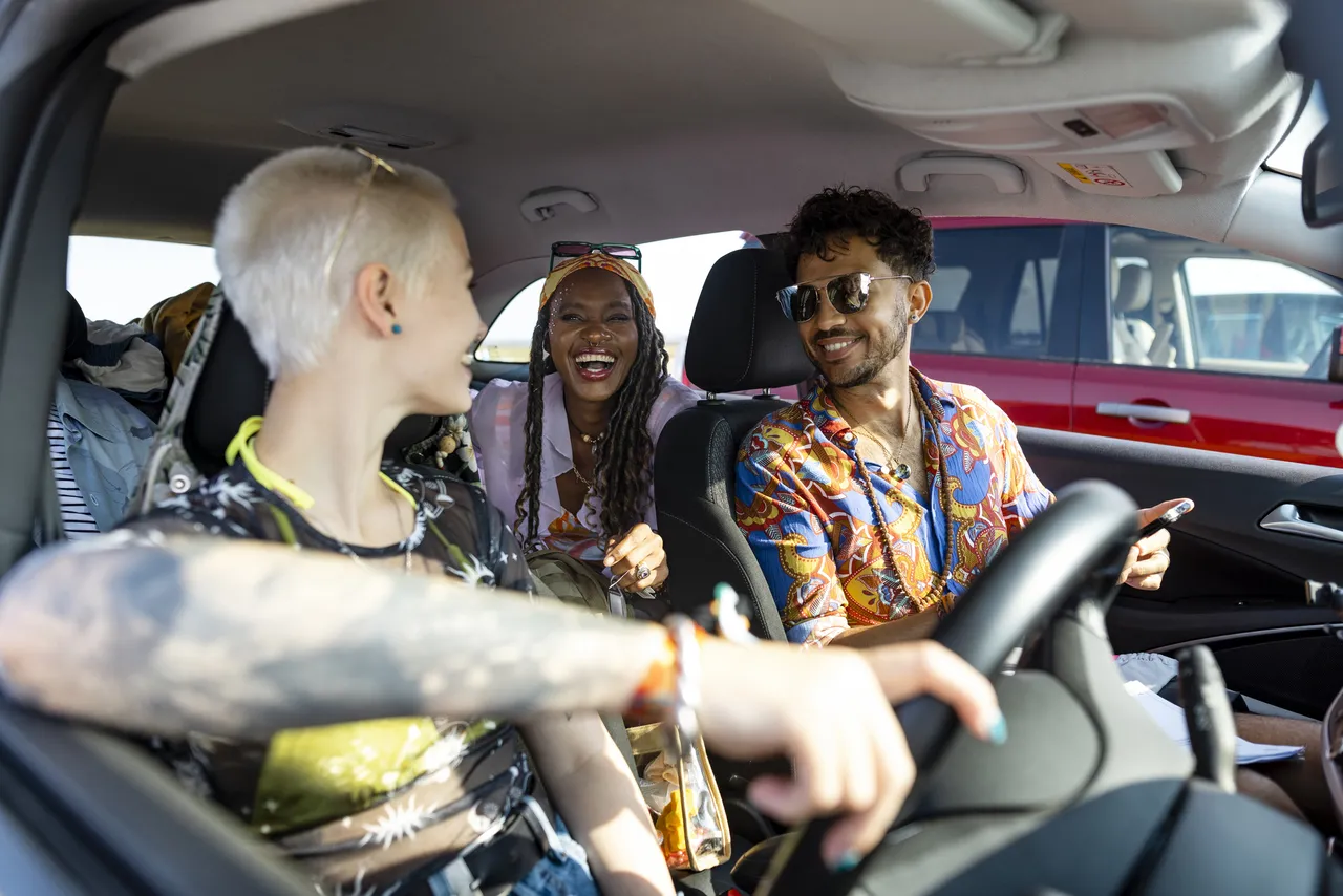 Friends sitting in a car after parking up at a festival in Lindisfarne, North East England.