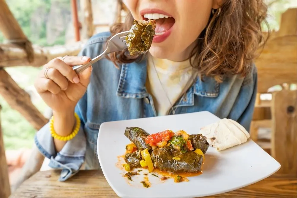 Woman eating dolmades — Shutterstock