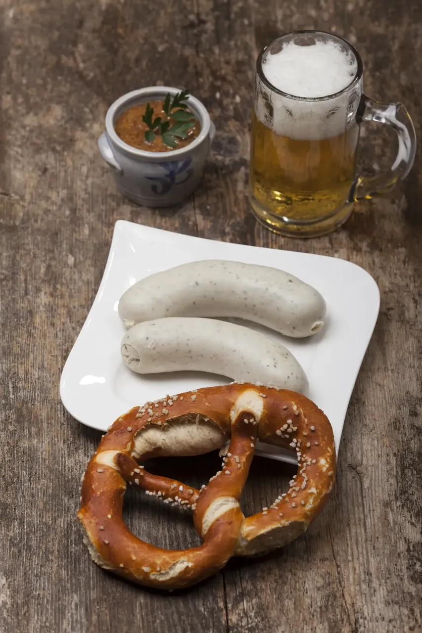 Weißwurst with pretzel and stein of beer on table — Getty Images