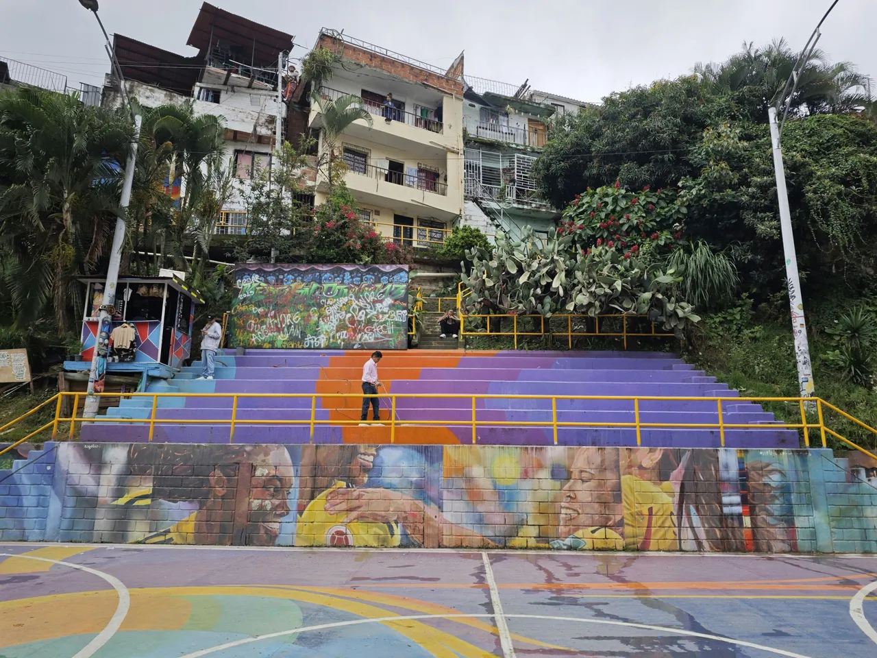 Tourist walking through Comuna 13 in Medellín, Colombia, surrounded by colorful graffiti murals on walls.