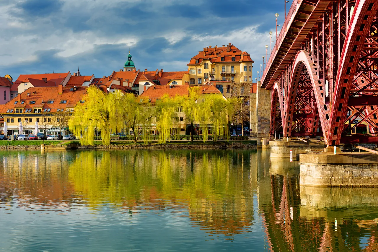 A Dráva folyó felületén tükröződő Glavni Most (Glavni híd) a szlovéniai Mariborban, egy napos tavaszi estén.