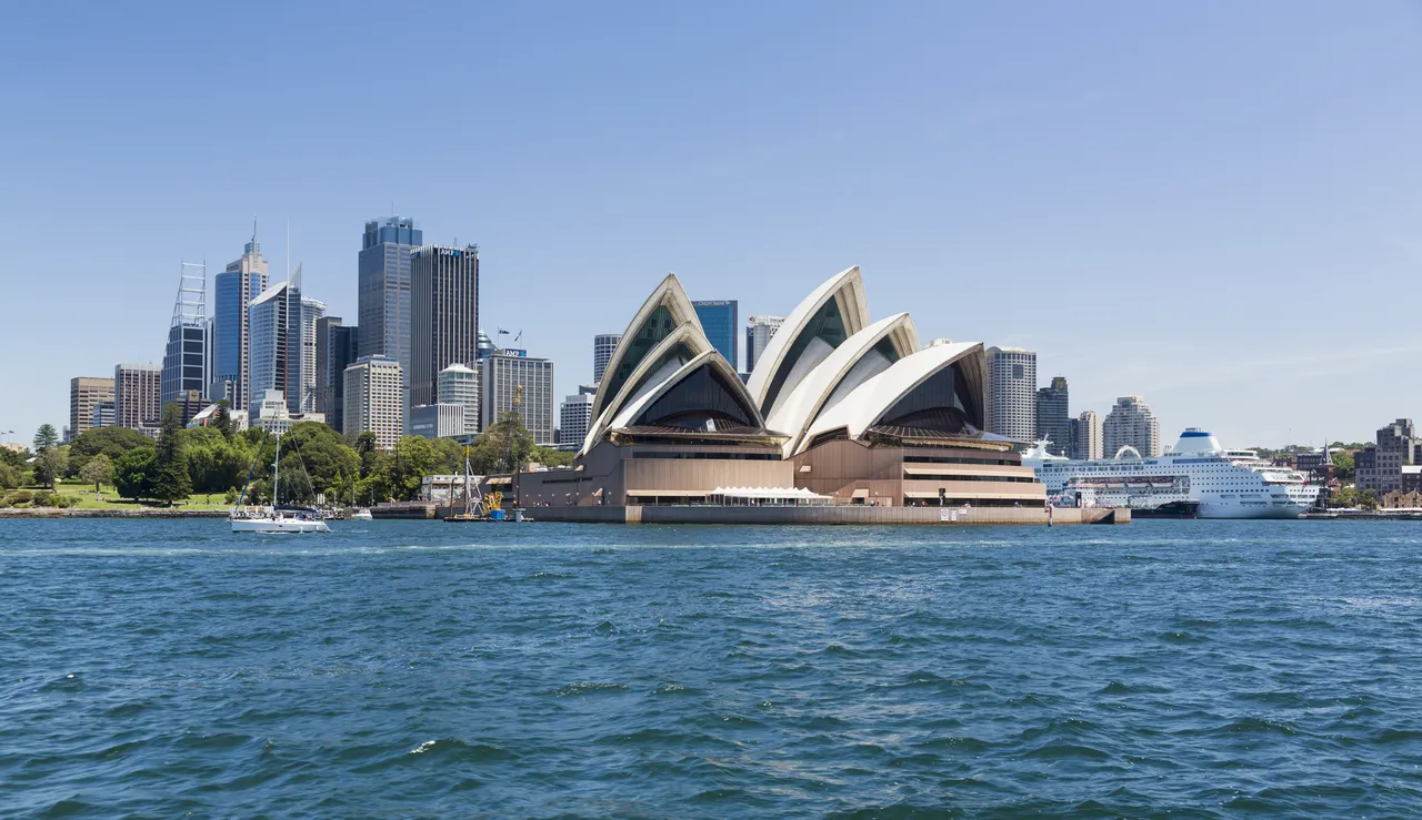 Central business district of city of Sydney with the Pacific Pearl Cruise ship docked in the harbor. View includes the Opera House, and a broad view of the water in the harbour