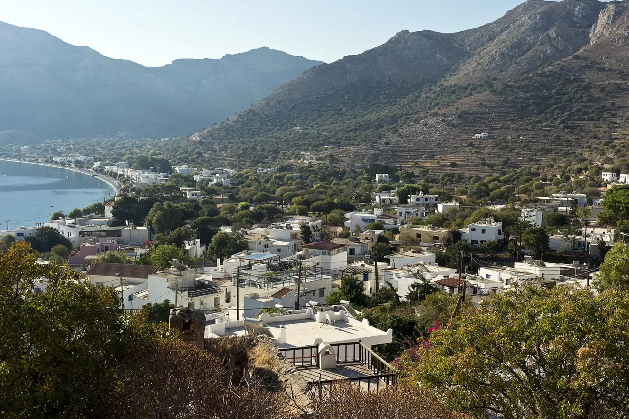 A scenic viewpoint in Tilos, Greece, offering panoramic views of the island’s rugged terrain, the Aegean Sea, and distant islands under a clear blue sky
