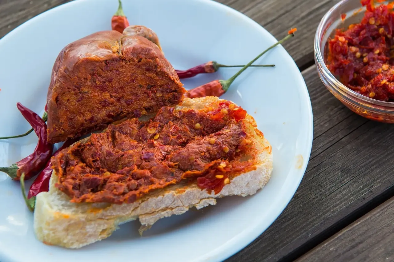 Kanapka z pikantna kiełbasa nduja na talerzu.