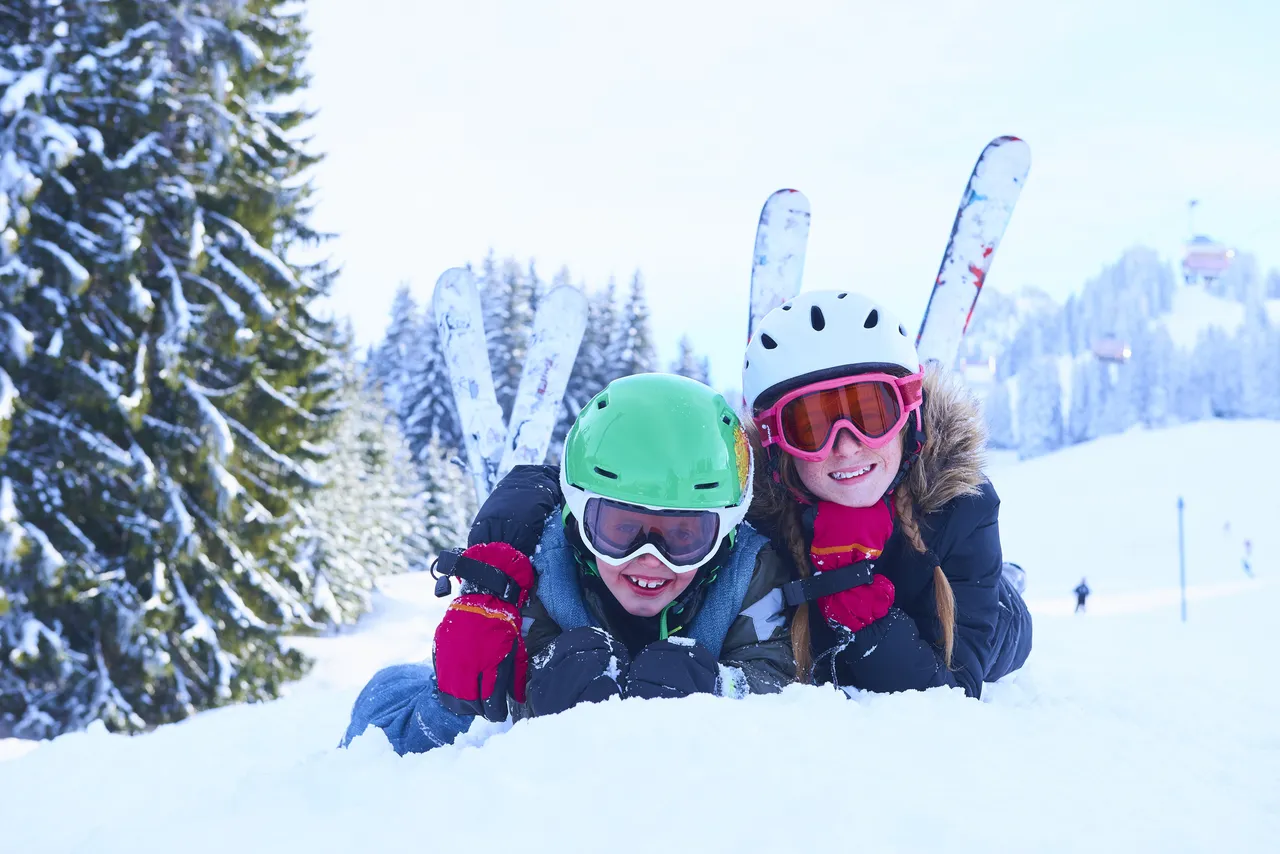 A teenage girl with her brother lying on snow for a picture, Switzerland