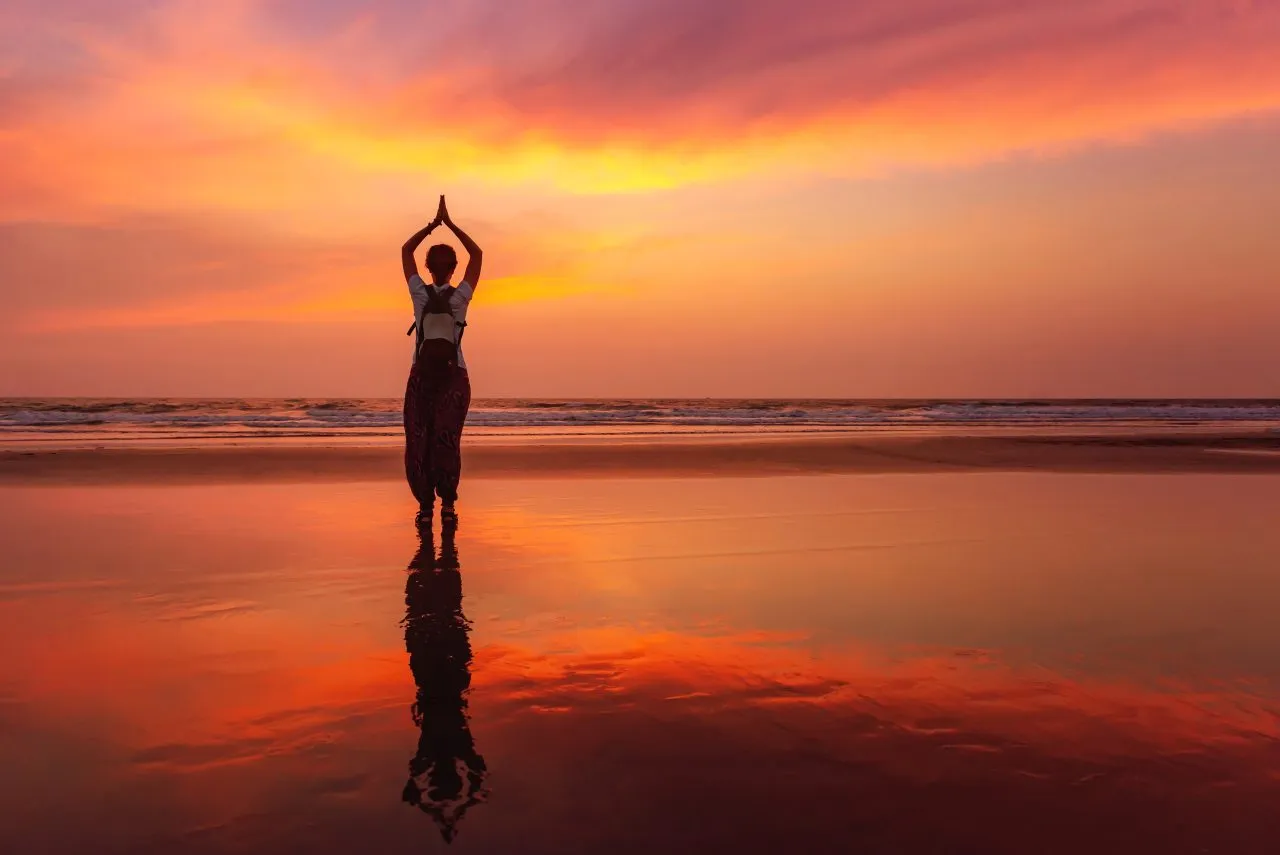 Beautiful yoga meditation reflection on water Goa beach on sunset