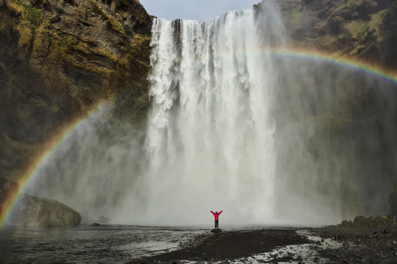 Tęcza i dziewczyna na tle wodospadu Skogafoss na Islandia