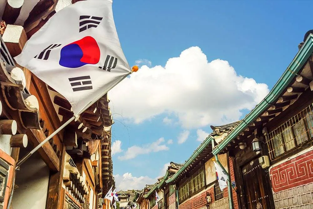 Tradicionális koreai stílusú építészet a szöuli Bukchon Hanok faluban, elöl a dél-koreai zászló lobog — Shutterstock