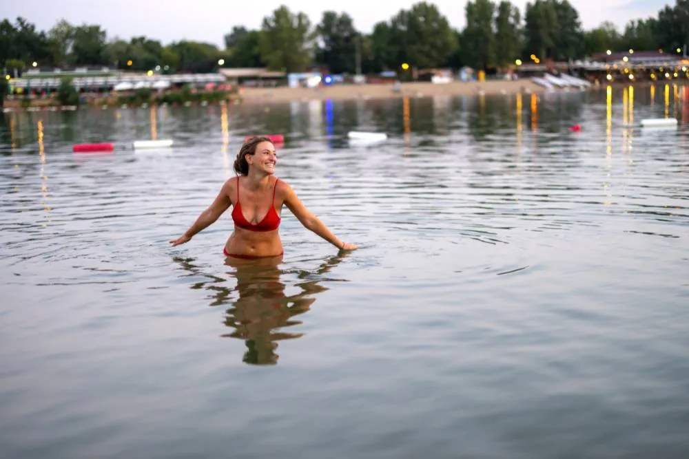 Woman in water at city beach in early evening — Getty Images