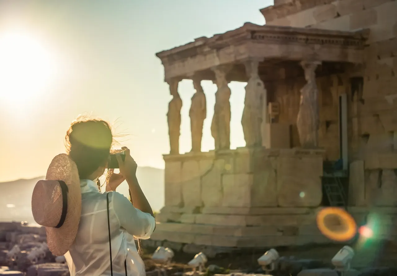 Tourist takes a photograph of Acropolis in the early evening sunlight