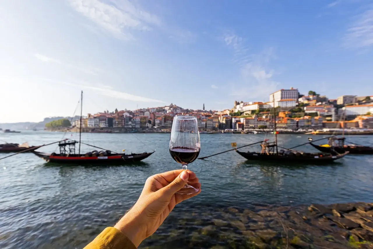 Kieliszek wina Porto na tle zabytkowej architektury centrum Porto i brukowanych uliczek.