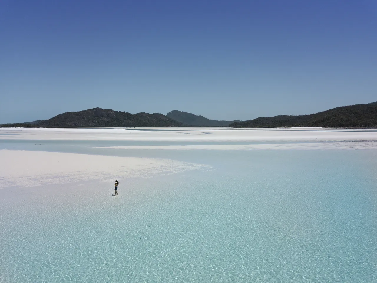 Girl walking on Whitehaven Beach in shallow water (Queensland, Australia).