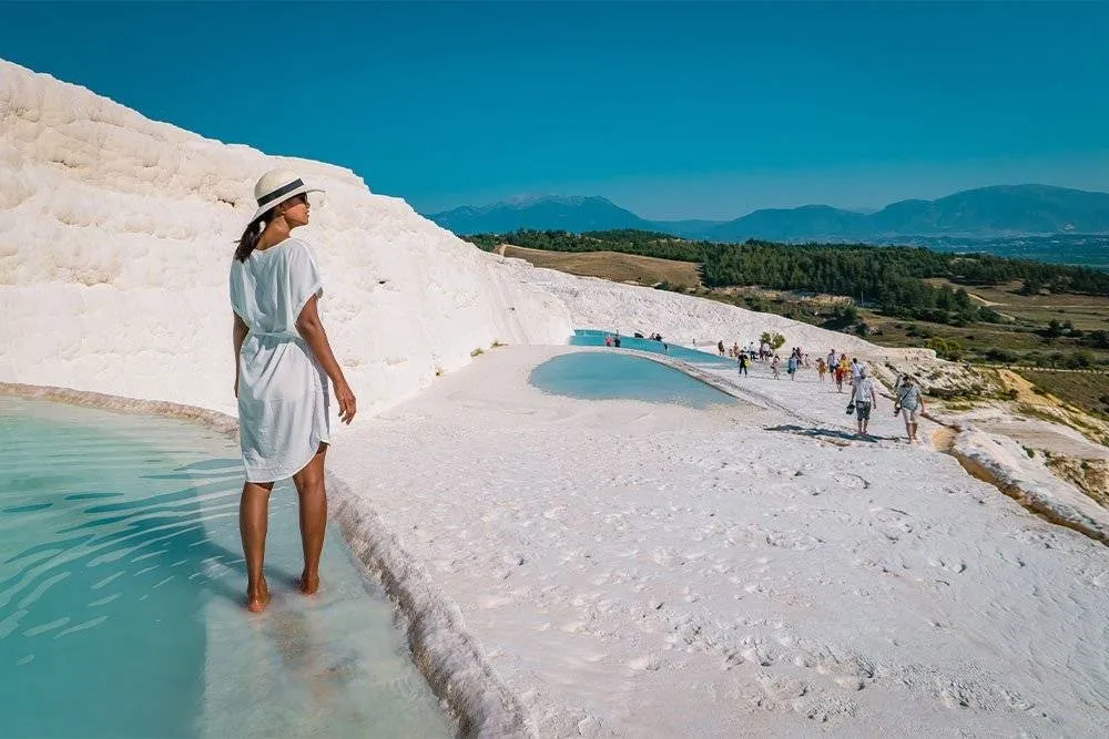 Nő sétál a travertin teraszos medencék között Pamukkale-ban