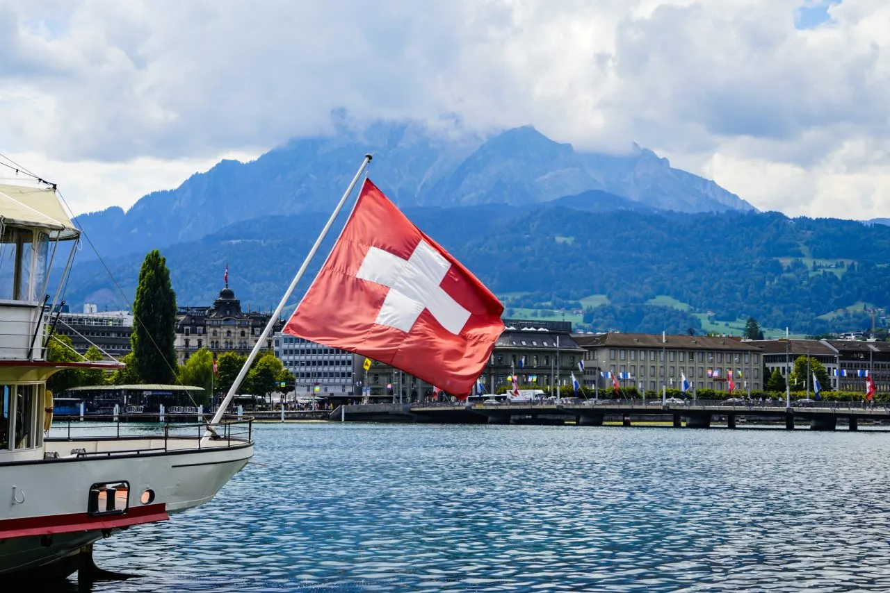 A view of a Swiss flag on a boat on lake Lucerne and Lucerne city in central Switzerland