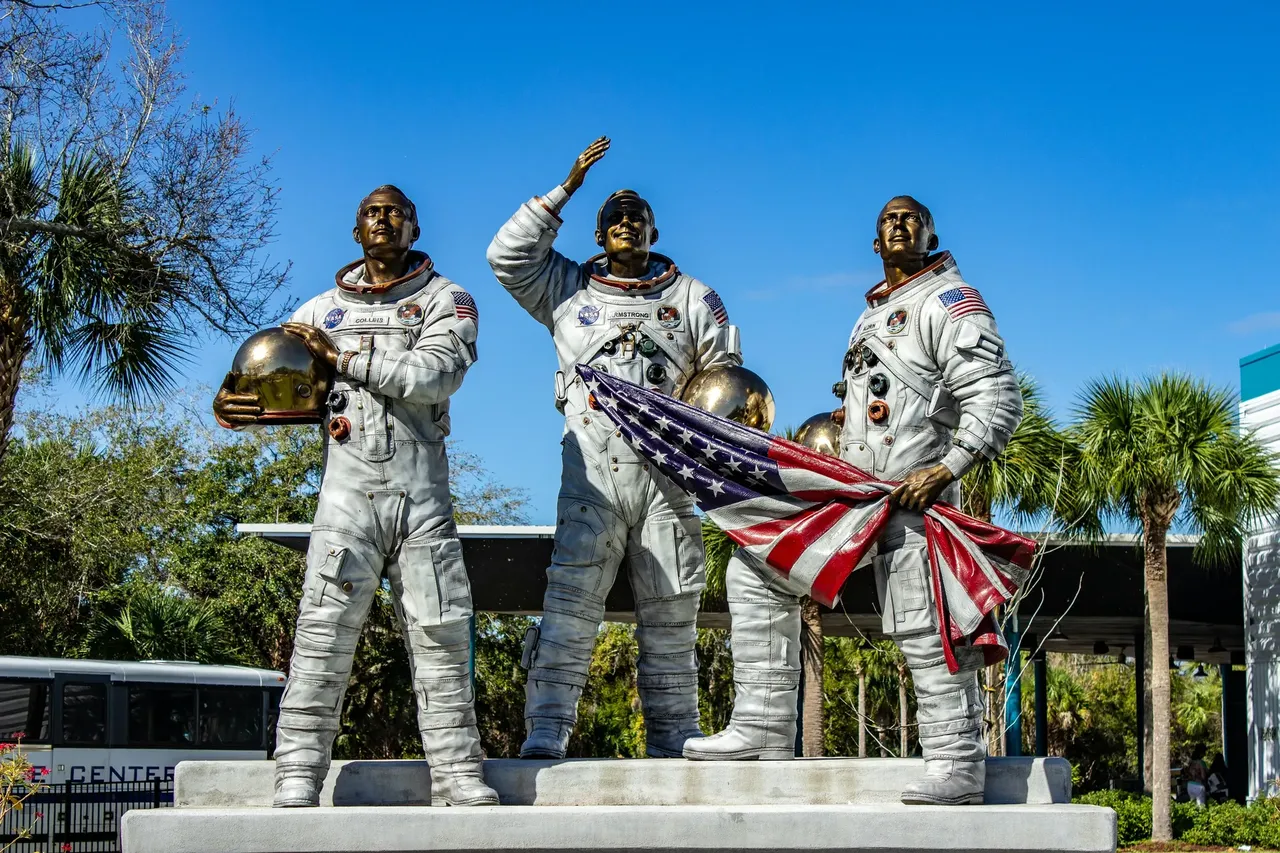 The Kennedy Space Center featuring three astronaut statues standing in front of a rocket display, symbolizing space exploration.