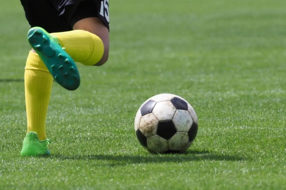 Amateur football player kicking football — Shutterstock