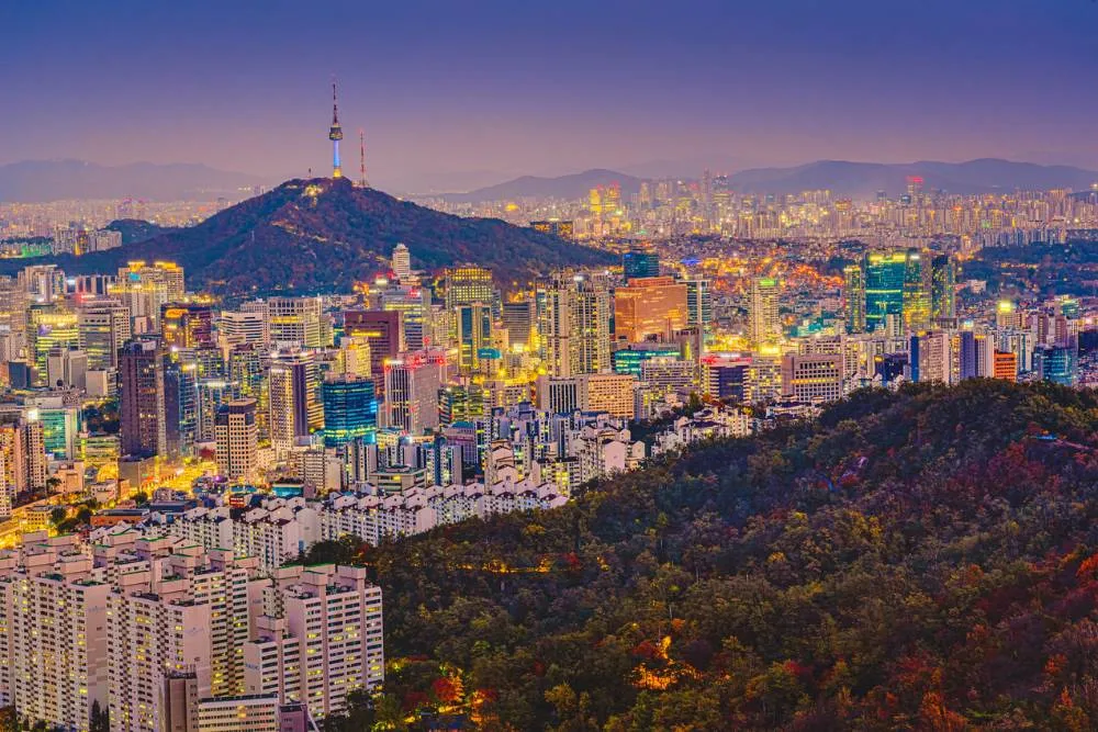 Vedere din unghi înalt a turnului Namsan Seoul înconjurat de peisajul urban al Seulului iluminat cu lumini în lumina amurgului de pe muntele Inwang. Seoul, Coreea de Sud
