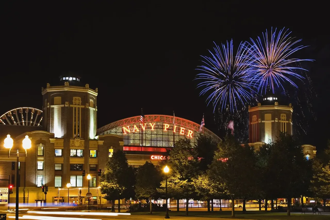 Barevná show ohňostrojů osvětlující oblohu nad molem Navy Pier s panoramatem Chicaga v pozadí.