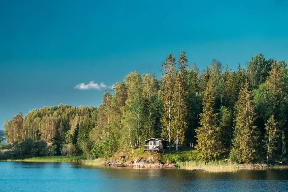 View of solitary summer cabin in the forest by a lake in Sweden — Shutterstock
