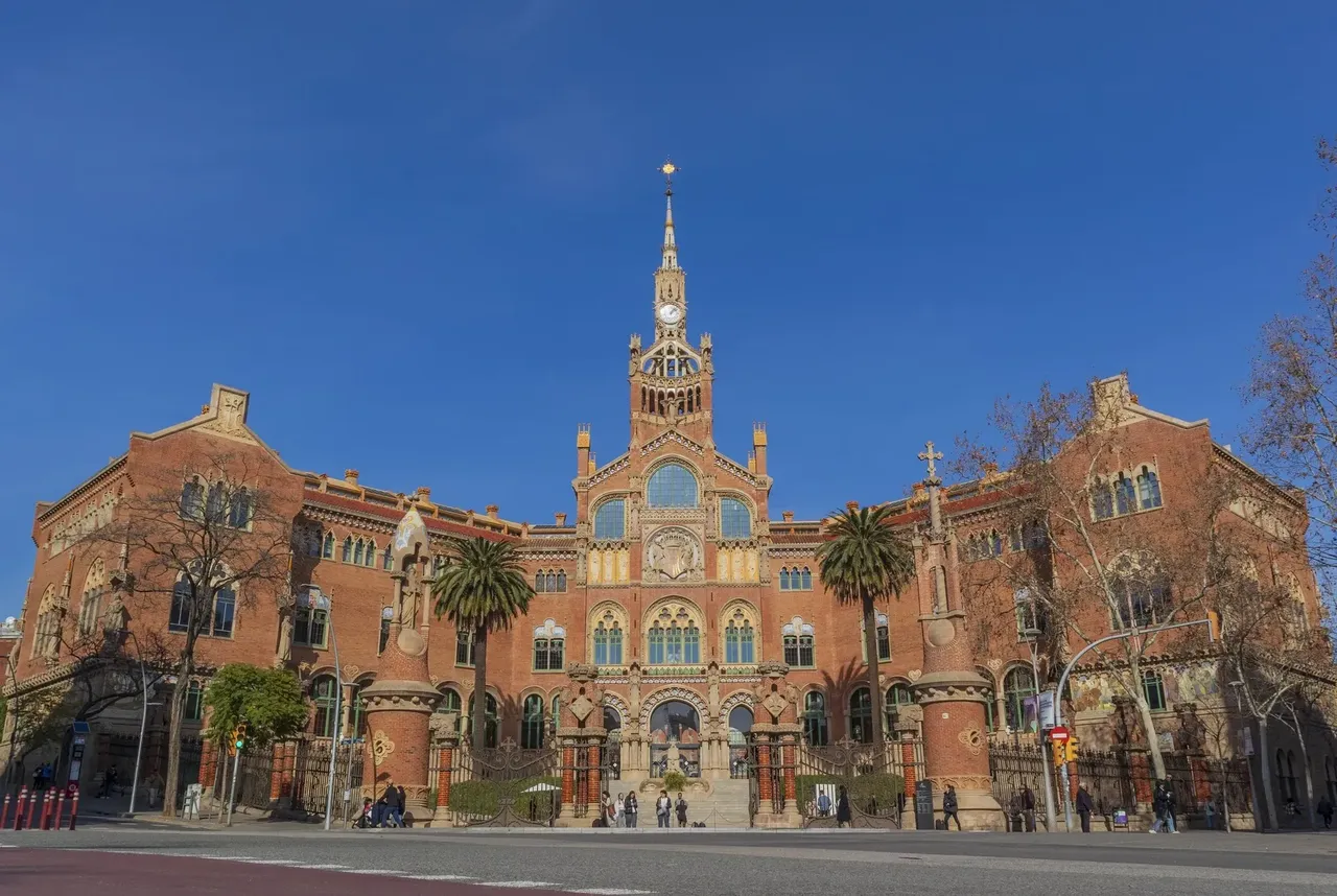 Exteriorul ornamentat al Spitalului de Sant Pau, cu arhitectura sa modernistă, având sculpturi și mozaicuri detaliate.