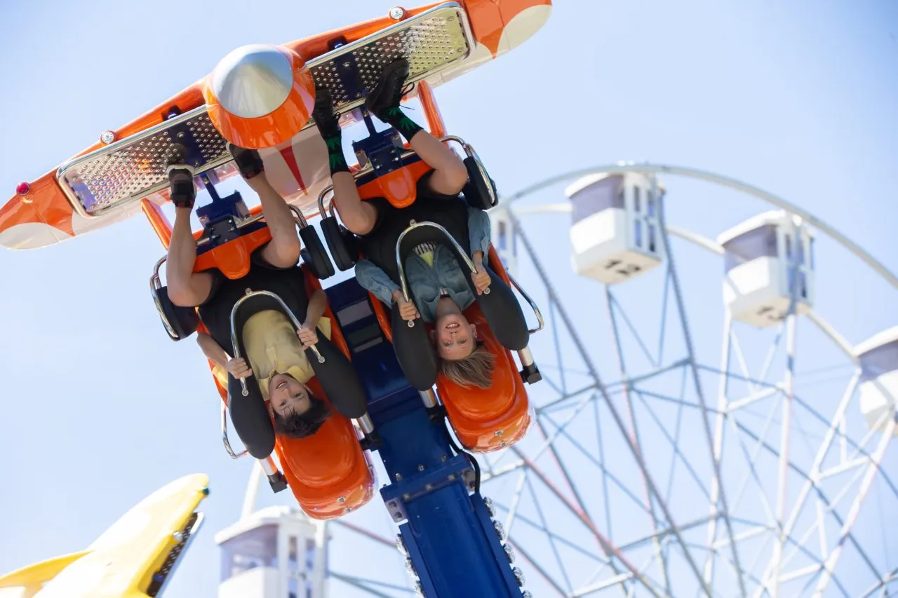 Teenagers ride head down on a carousel. Extreme rides in the park. Disney World, Orlando