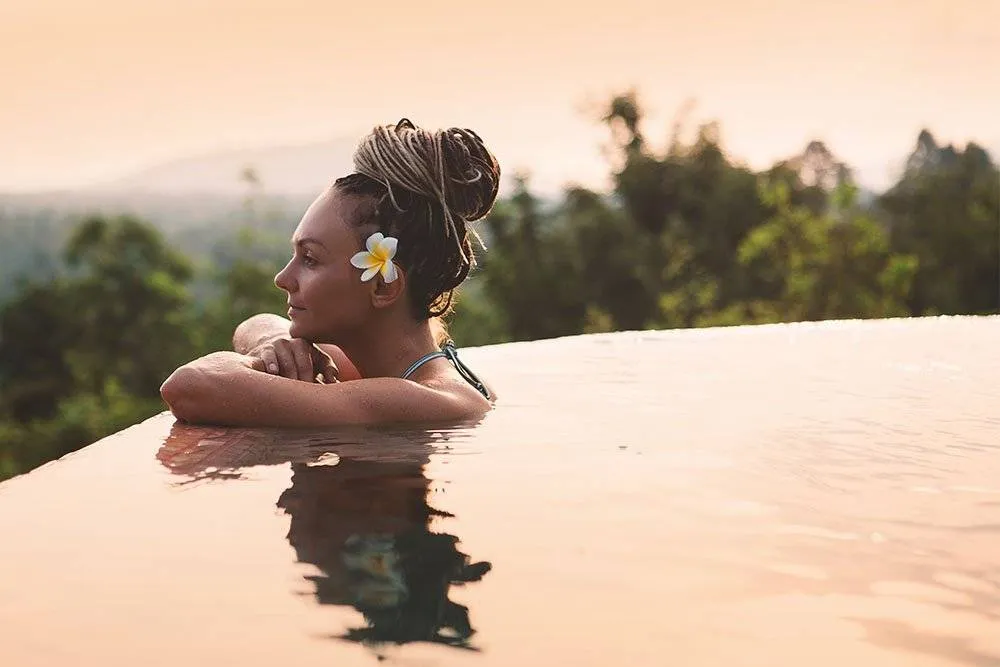 Woman in outdoor infinity pool at dusk — Shutterstock
