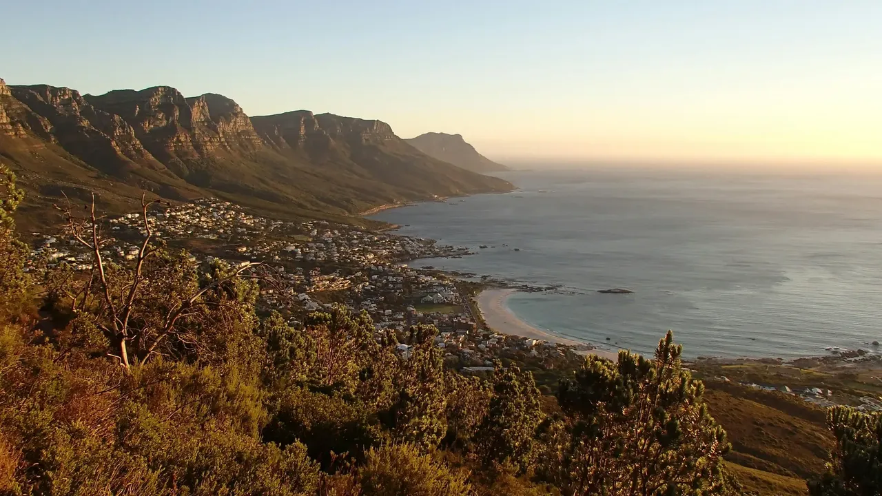 A golden sunset over the Twelve Apostles mountain range and coastal town in Cape Town, South Africa