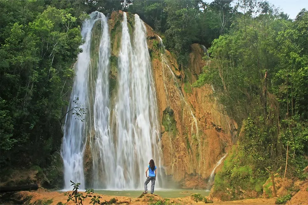 Person stood at the foot of a waterfall in Dominican Republic — Shutterstock