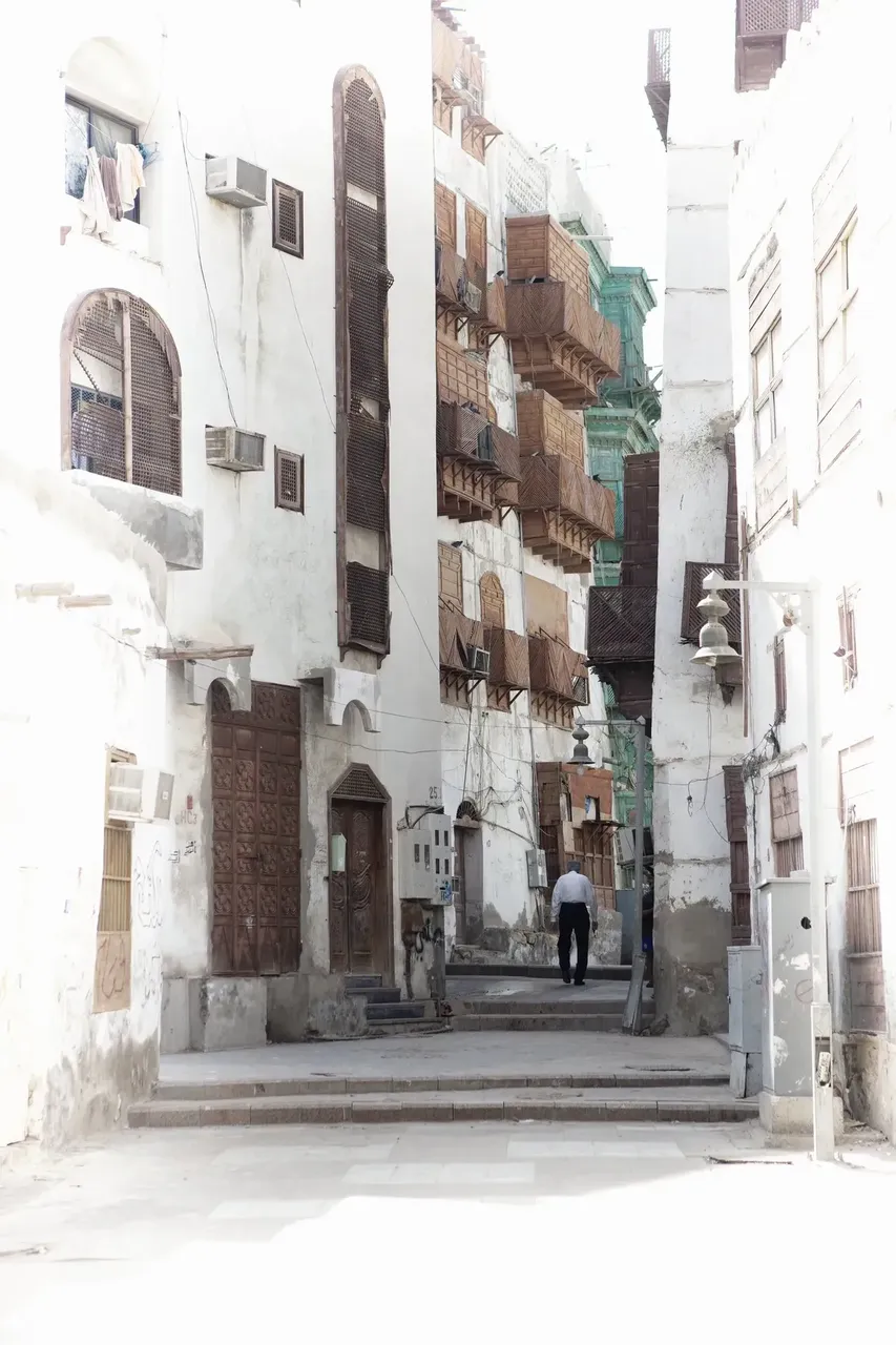A serene, narrow street lined with traditional white buildings featuring wooden latticed windows in Al-Balad, Jeddah