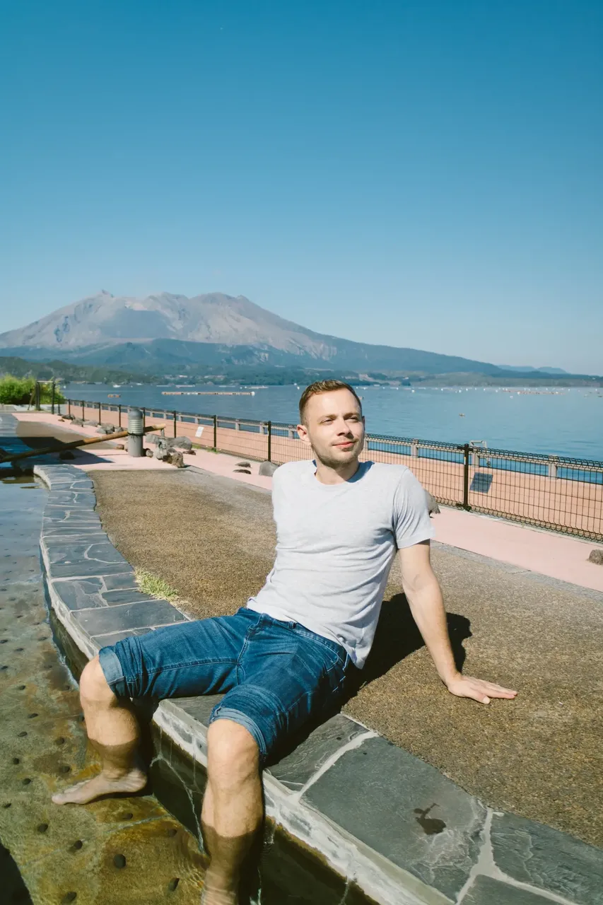 Man at hot spring foot bath with Sakurajima volcano in background — Getty Images