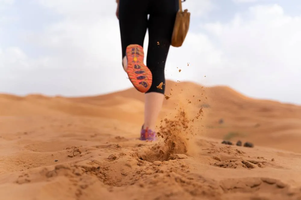 Legs of person running in Sahara Desert — Getty Images