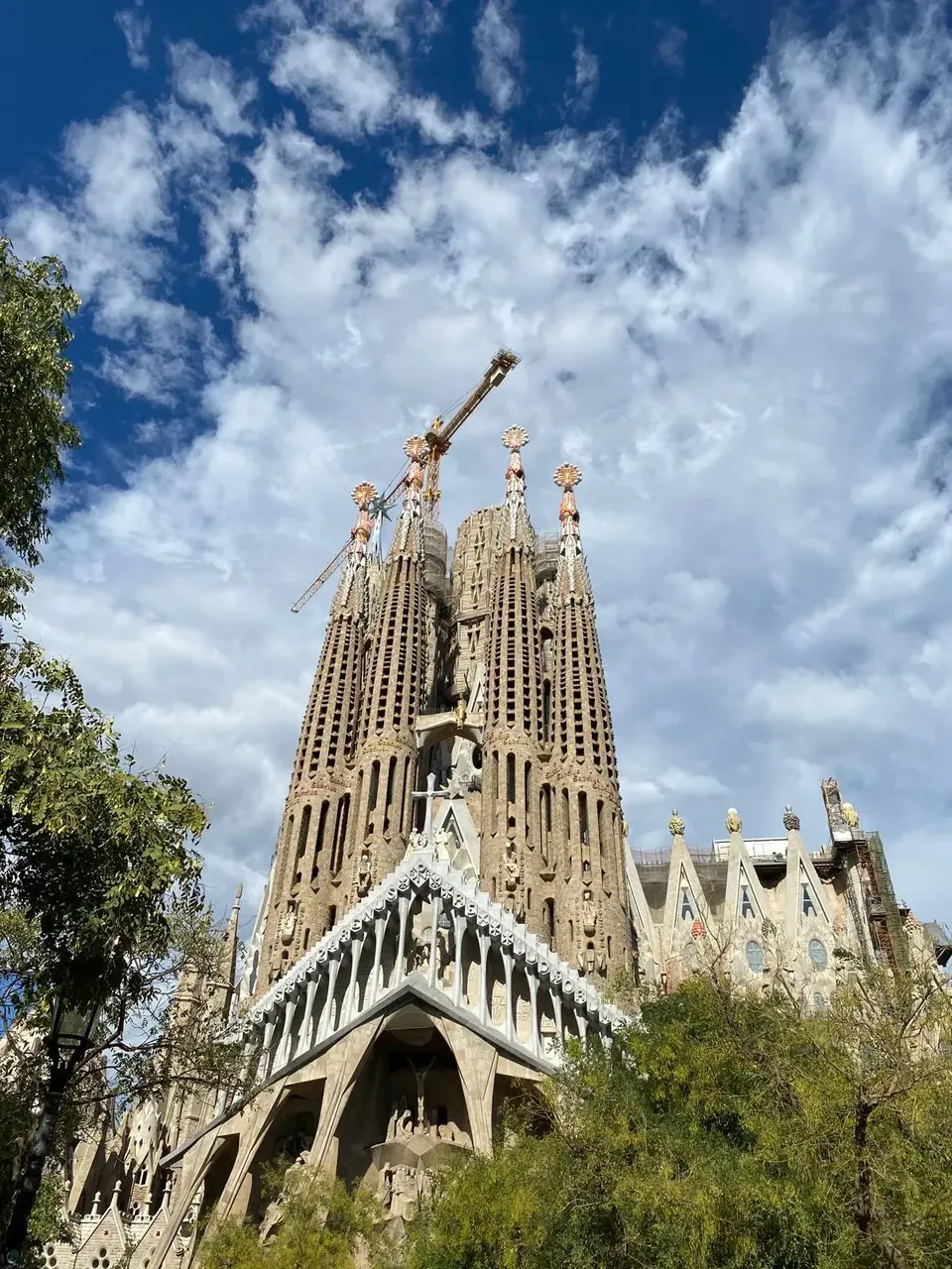 O vedere a Sagrada Familia din Barcelona, evidențiind turlele sale complexe și fațadele detaliate pe fundalul unui cer albastru senin.